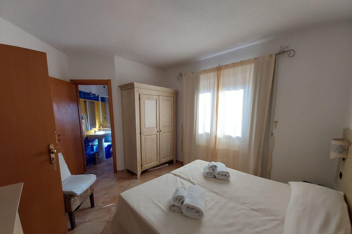 Ein Hotelzimmer mit einem Bett, einem Kleiderschrank, einem Badezimmer mit Waschbecken und einem Sessel.