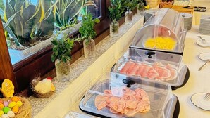 A buffet setup with various food items in transparent containers, a window with plants, and a view of a building outside. - Hotel Il Faro di Molara (Loiri Porto San Paolo)