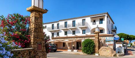 A hotel with multiple balconies, a stone tower, and a clear blue sky.