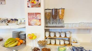 A buffet setup with various food items, including fruits, cereals, and beverages.