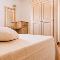 A bedroom with a bed, a dresser, and a wardrobe.