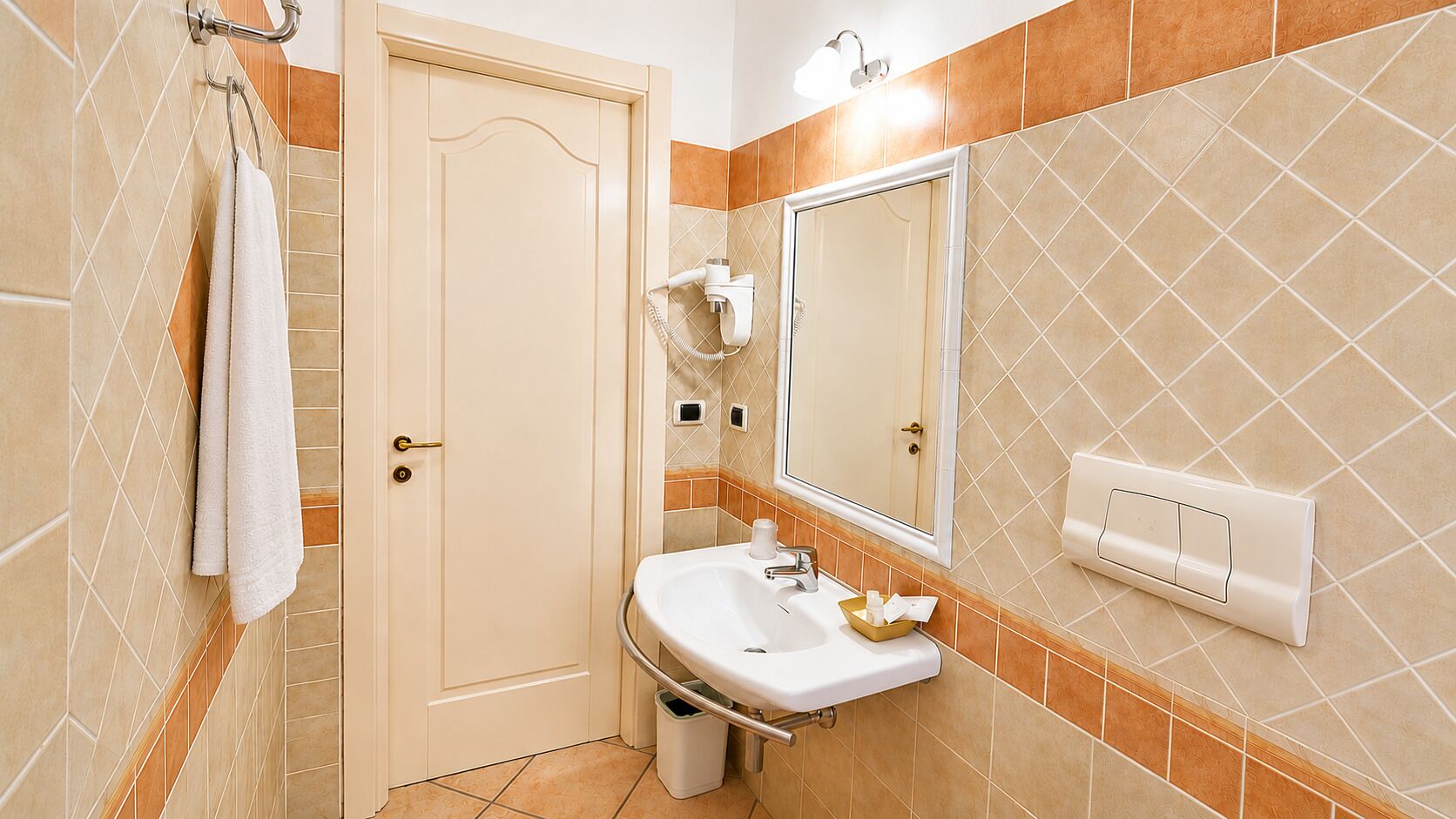 A bathroom with a sink, mirror, towel rack, and a door.