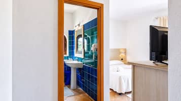Une chambre d’hôtel avec une salle de bain carrelée de carreaux bleus, comprenant un lavabo et un miroir.