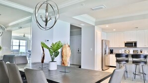 A modern kitchen with white cabinets, stainless steel appliances, and a bar area with stools. - 4 BR En Soleil Directly on Gulf, Beautiful With Free Beach Chairs.  6th Floor (Panama City)