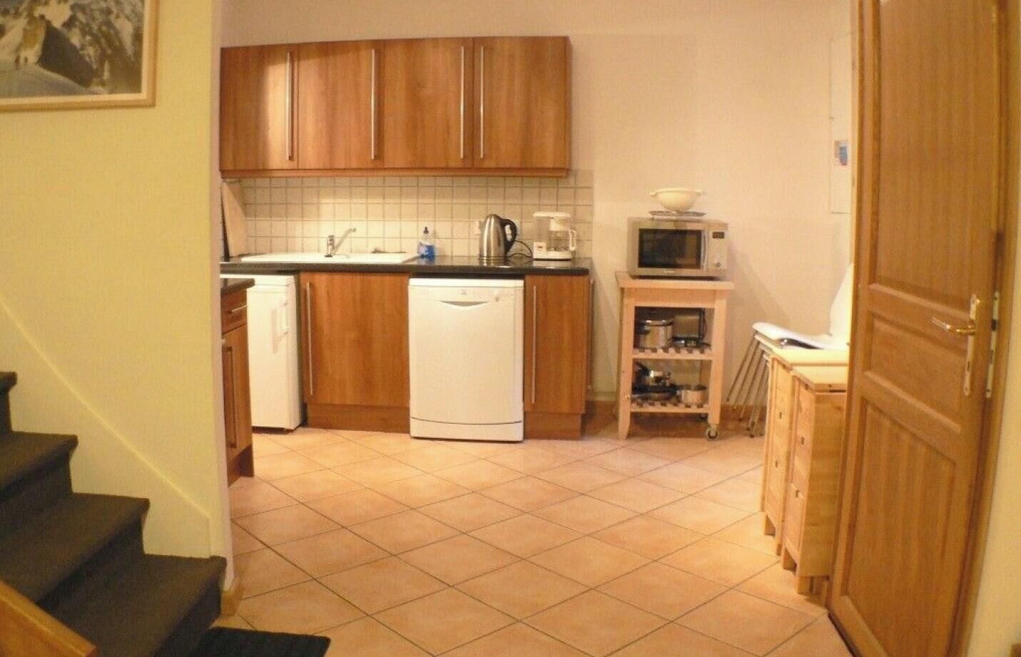 Eine Küche mit Holzausstattung, einem Geschirrspüler, einer Mikrowelle und einem kleinen Regal mit Küchenutensilien.