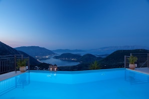 An infinity pool with a view of a coastal landscape at dusk. - Luxury Villa With Stunning Views in Lefkada (Lefkada)