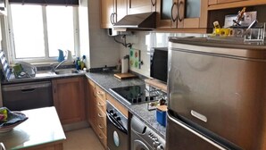 Eine Küche mit Holzausstattung, einem Edelstahlkühlschrank, einem Geschirrspüler und einer Waschmaschine.