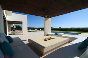 A modern outdoor lounge area with a pool, white furniture, and a clear view of the landscape.