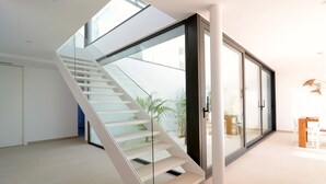 Ein modernes Interieur mit einer Glasstiege, die zu einem Balkon führt.