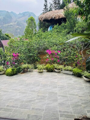 A garden area with potted plants and a thatched-roof structure. - Plum Hillside Lodge (Dong Van)
