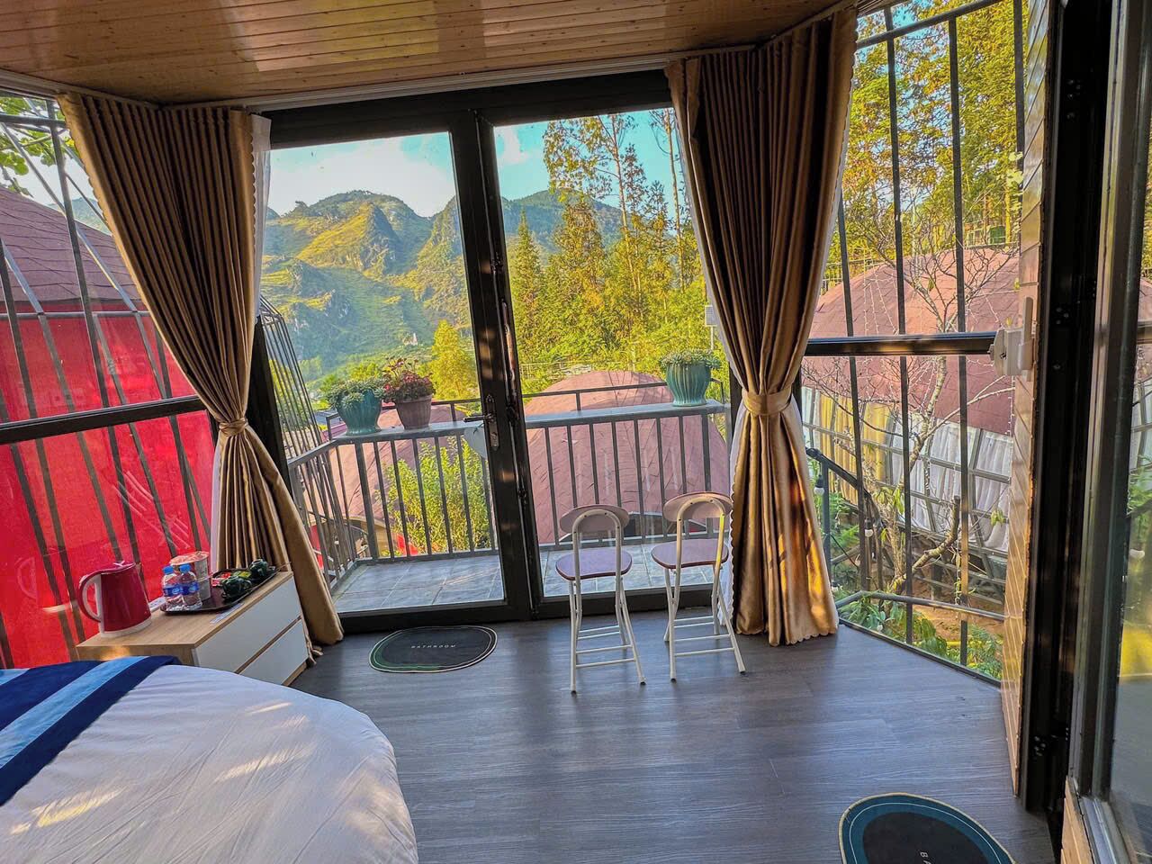 A balcony with a view of mountains, a bed, and a table with chairs.