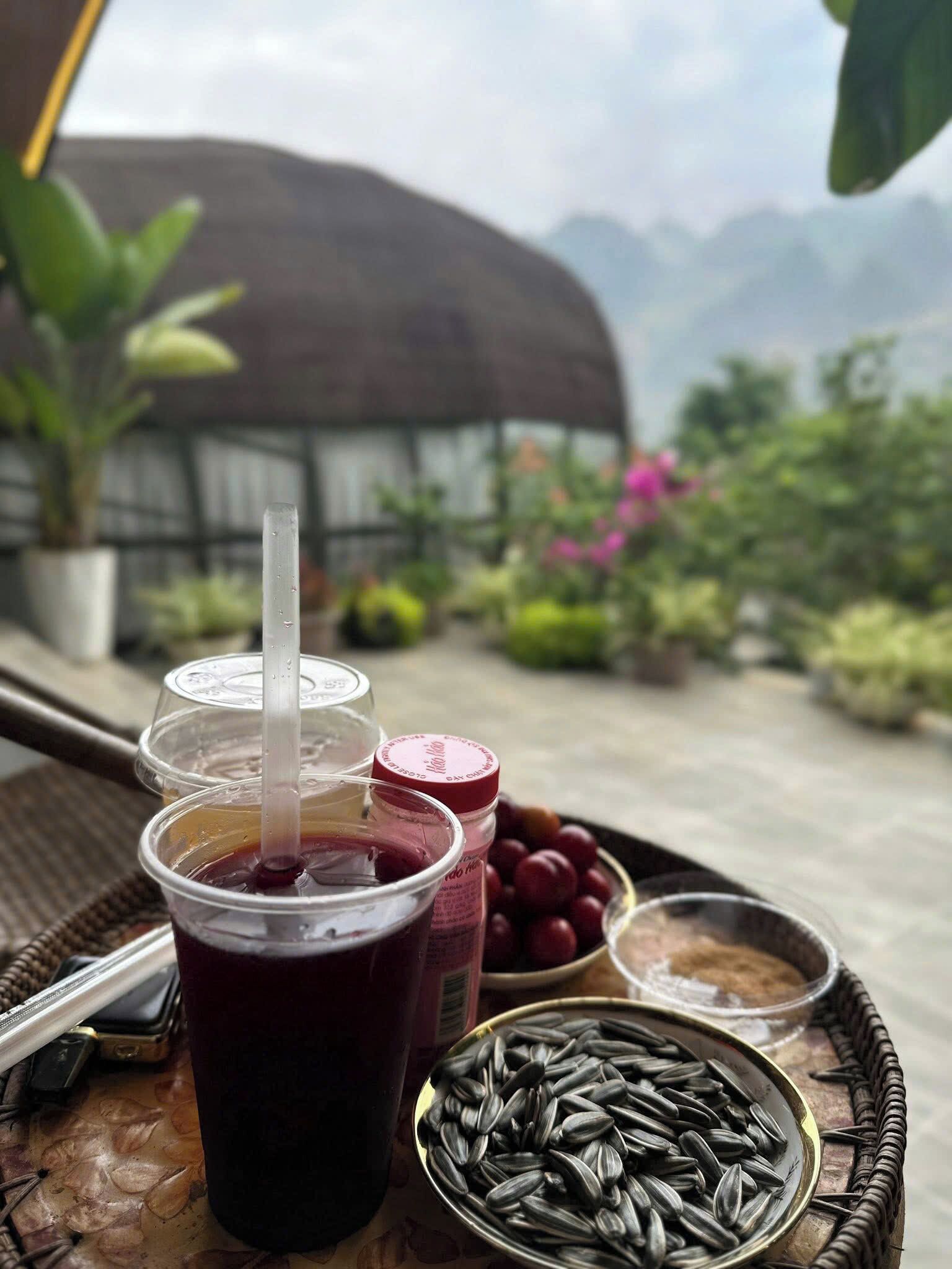 A tray with a drink, a jar of jam, a bowl of grapes, and a bowl of sunflower seeds.