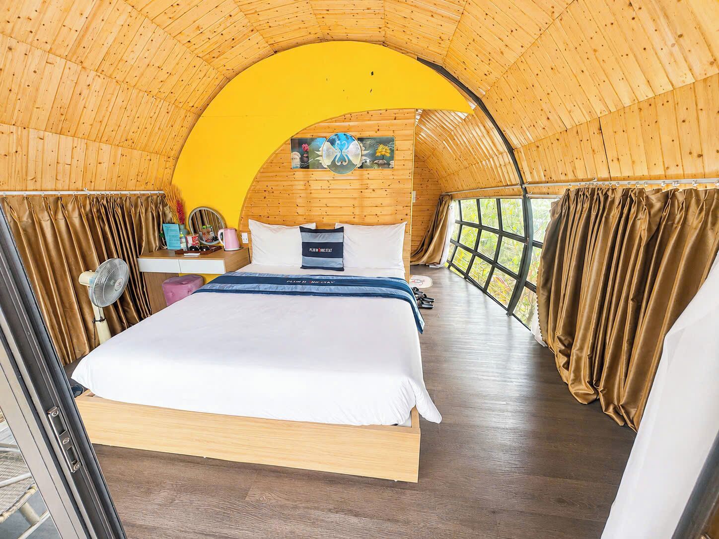 A cozy, circular room with a bed, a small table, and a window.