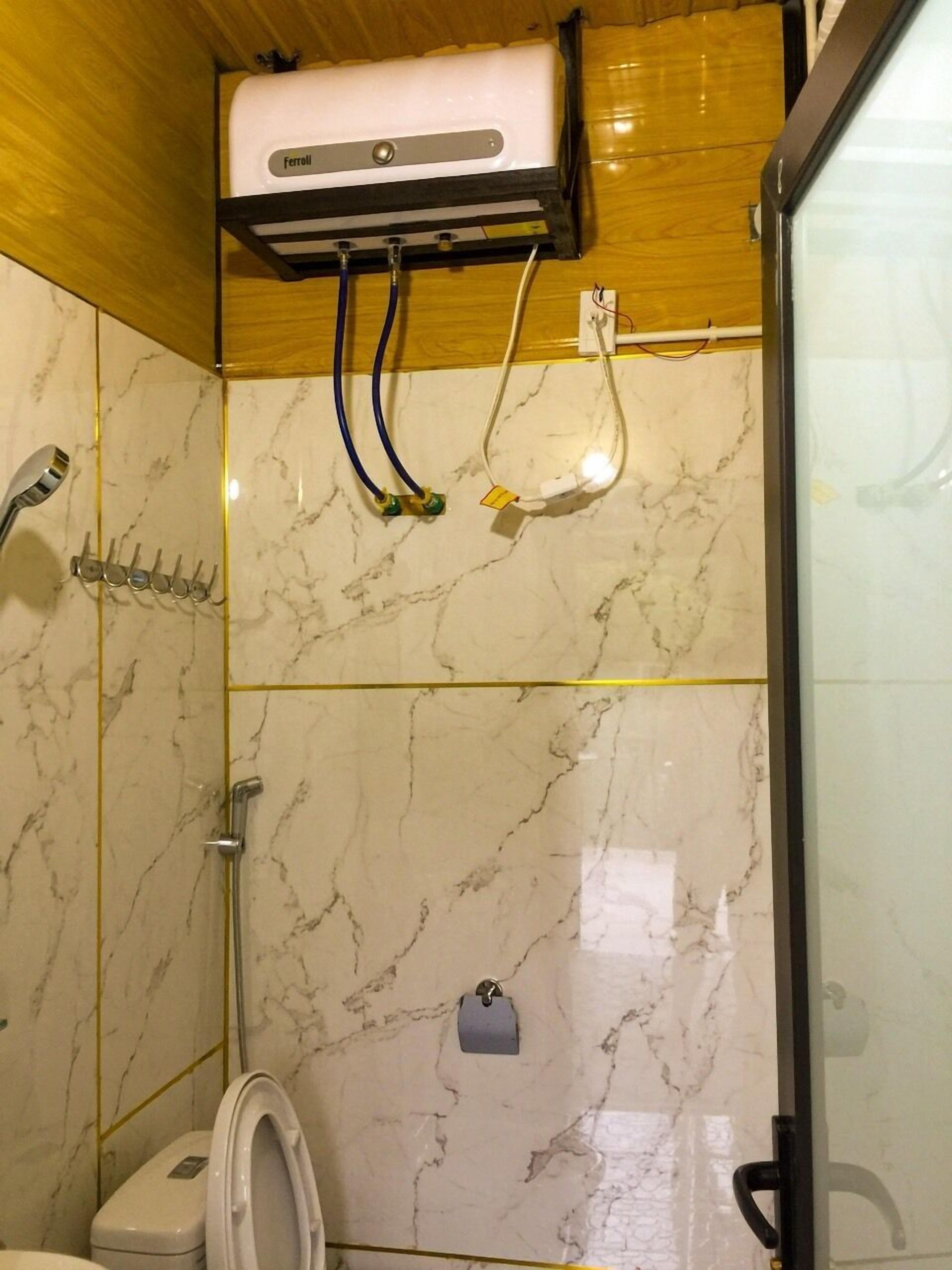 A bathroom with a toilet, shower, and an air conditioning unit mounted on the wall.