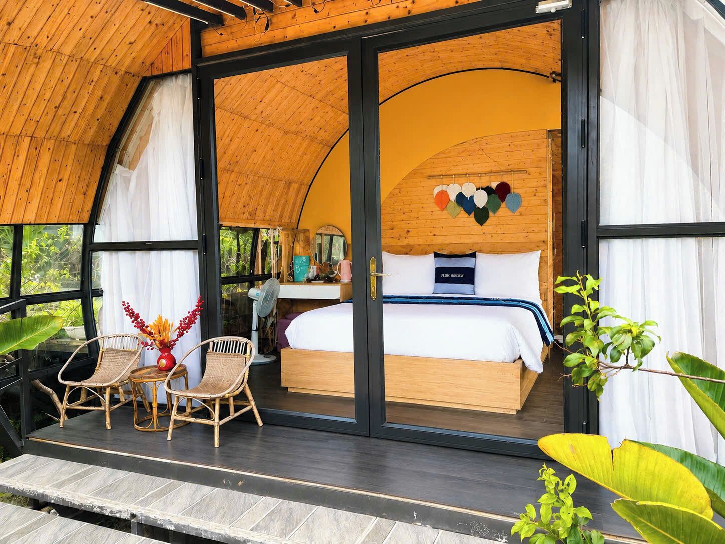 Quarto com uma cama, uma escrivaninha e uma cadeira. Há uma janela e uma porta.
