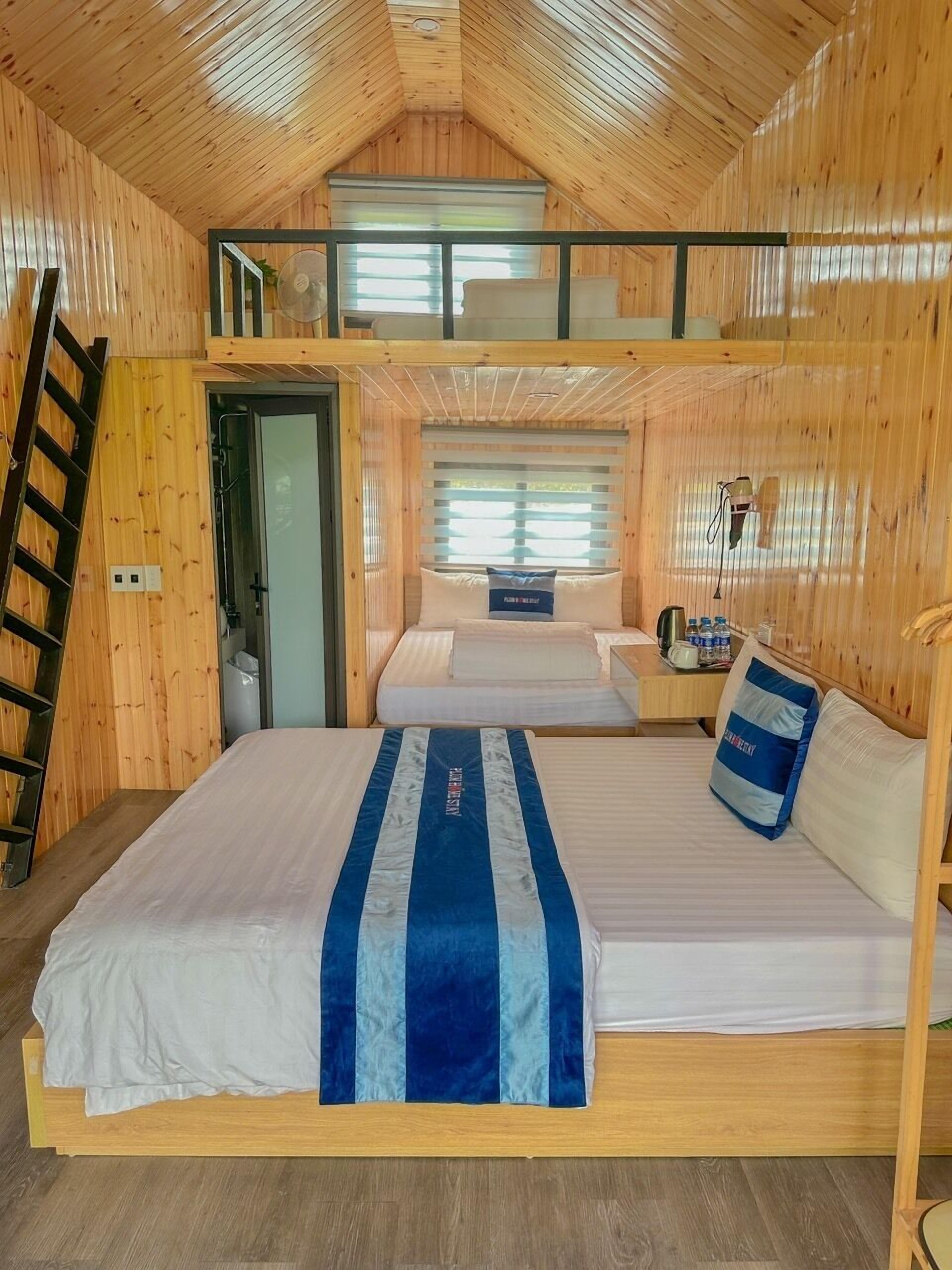 A bunk bed room with a loft bed, wooden walls, and a window with blinds.