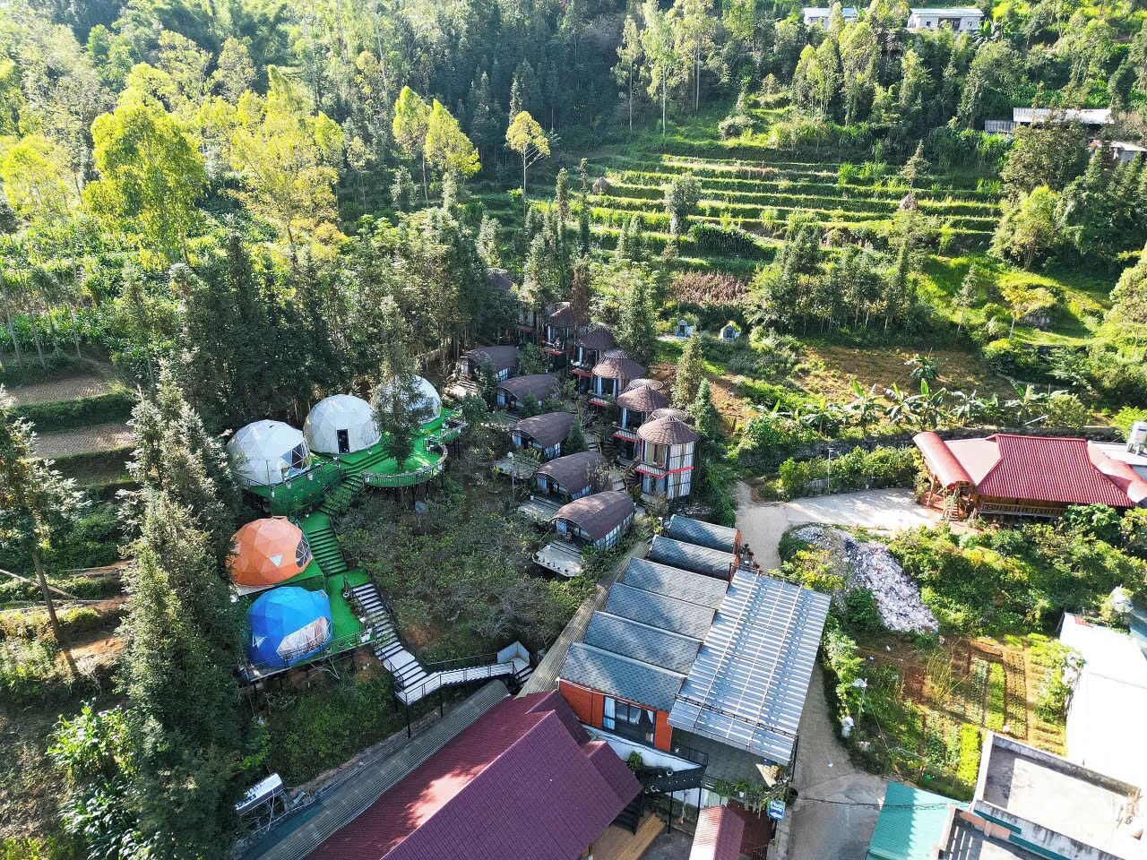 A rural setting with multiple dome-shaped structures, traditional buildings, and terraced fields.