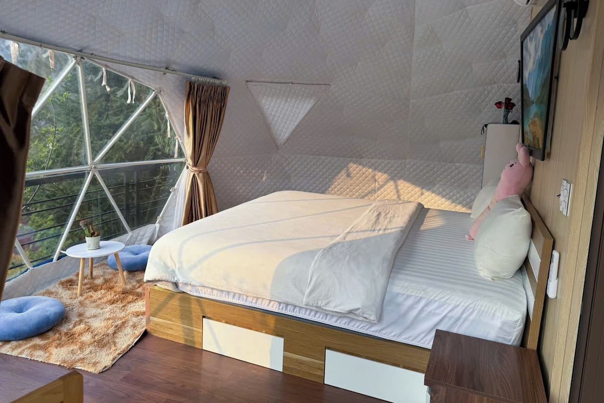 A cozy bedroom with a bed, a small table, and a window.