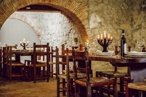 A rustic dining area with wooden tables and chairs, candles, and wine glasses. - Castle in Rome - Italy  (Collalto Sabino)