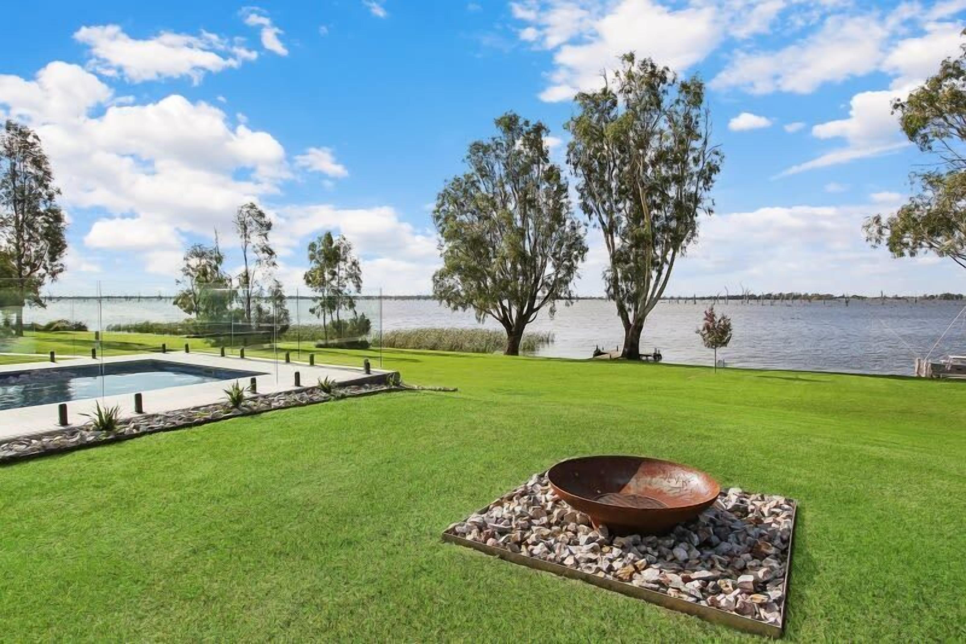 A pool, a fire pit, and a lake view.