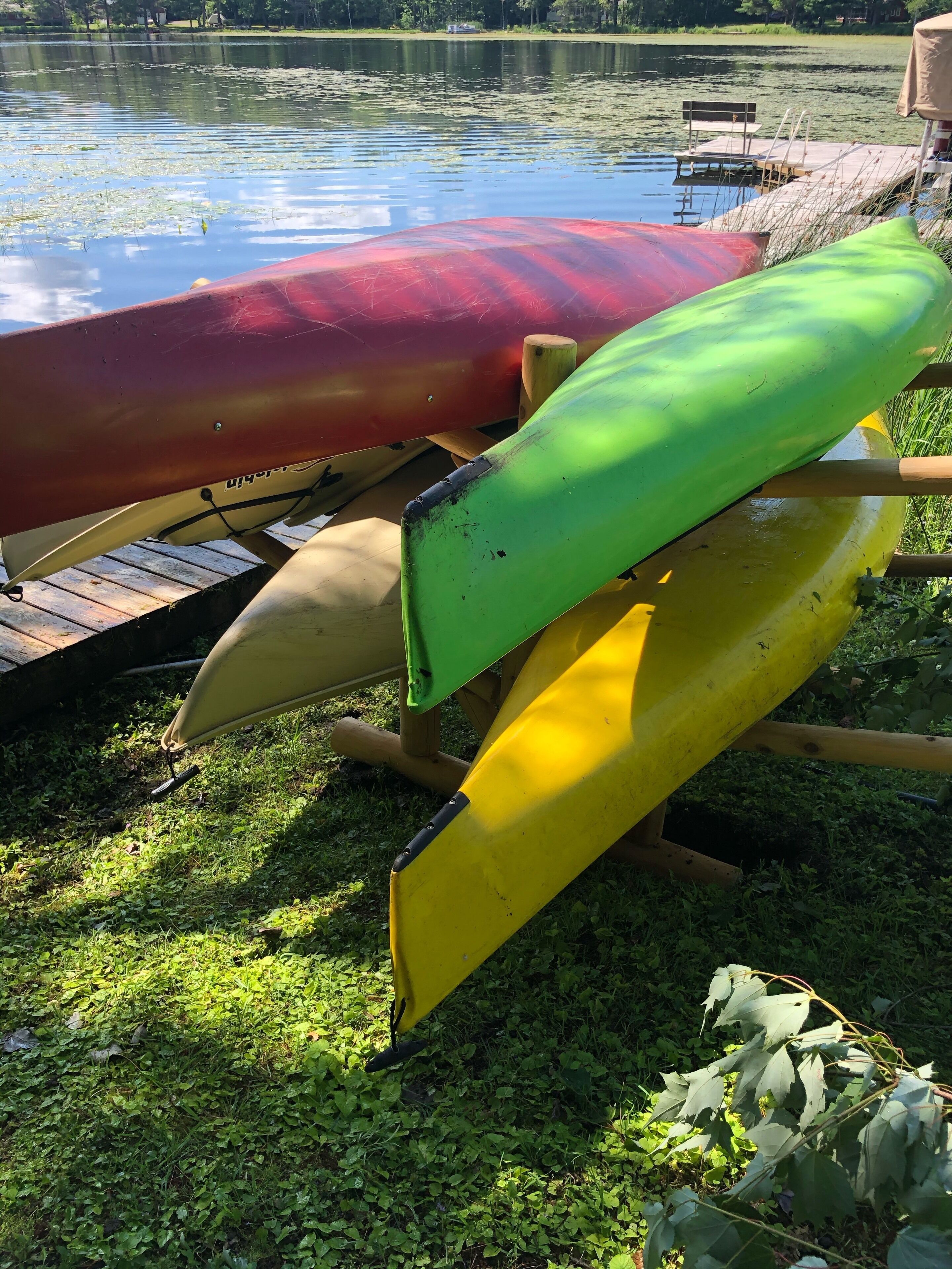 Una hilera de kayaks en un muelle de madera junto a un lago.