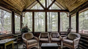A wooden cabin with a large windowed porch, wicker chairs, and a table. - Luxury 7,500‑Sq‑Ft Lakefront Lodge, Private Dock & Snowmobile Access (Hayward)
