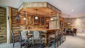 A rustic wooden cabin interior with a bar area, wooden walls, and a staircase. - Luxury 7,500‑Sq‑Ft Lakefront Lodge, Private Dock & Snowmobile Access (Hayward)