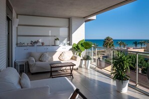 A balcony with a white sofa, a small table, and potted plants.