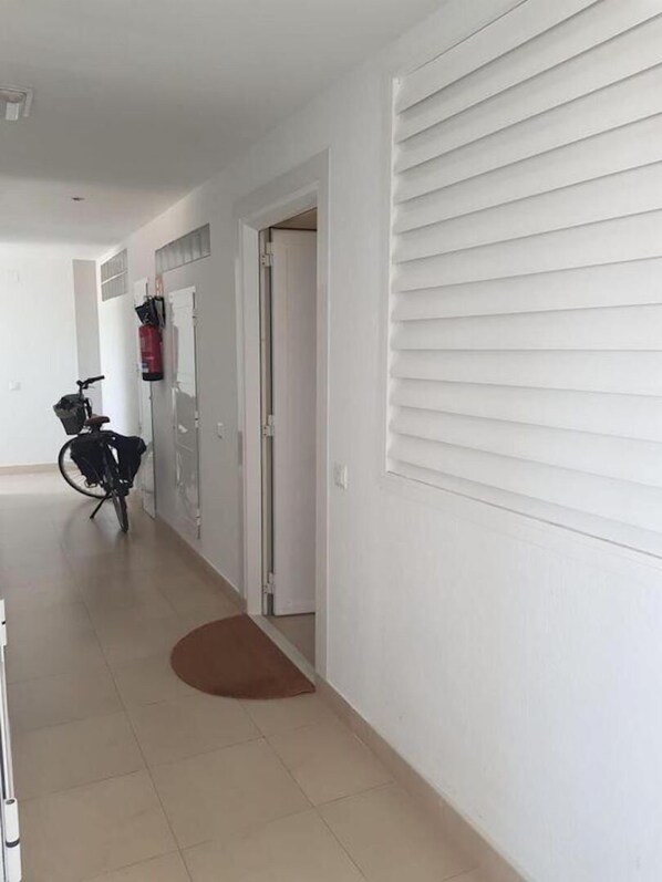 A hallway with a bicycle, a fire extinguisher, and a door leading to another room.