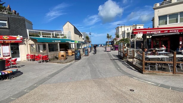 Una calle con mesas al aire libre, una cafetería y un restaurante.