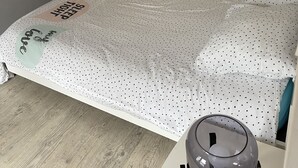 Un dormitorio con cama, mesita de noche, lámpara y armario.