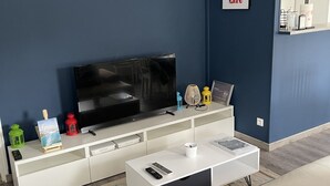 Una sala moderna con televisor de pantalla plana, mueble blanco de entretenimiento y un sofá.