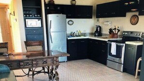 A kitchen with a dining table, chairs, a refrigerator, stove, and cabinets. - LaBamba - Great Condo for Adventurer in beautiful San Jose del Cabo (San José del Cabo)