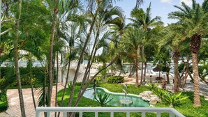 Een tropisch resort met palmbomen, een zwembad en een jachthaven op de achtergrond.