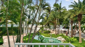 A tropical resort with palm trees, a swimming pool, and a marina in the background.