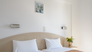 Habitación de hotel con cama, dos mesitas de noche, aire acondicionado de pared y una pequeña planta en maceta.