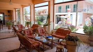 Un vestíbulo amplio con sillones de mimbre, una mesa de centro y plantas en macetas.