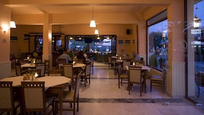Un restaurante con mesas y sillas, una zona de bar y amplias ventanas con vistas al exterior.