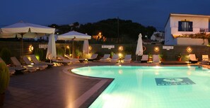 A swimming pool with lounge chairs and umbrellas, surrounded by a low wall and potted plants. - Hotel Akti Arilla (Corfu)