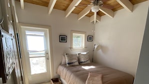 A bedroom with a bed, a ceiling fan, a window, and a door. - Water Island Cottage with a View  (St Thomas)