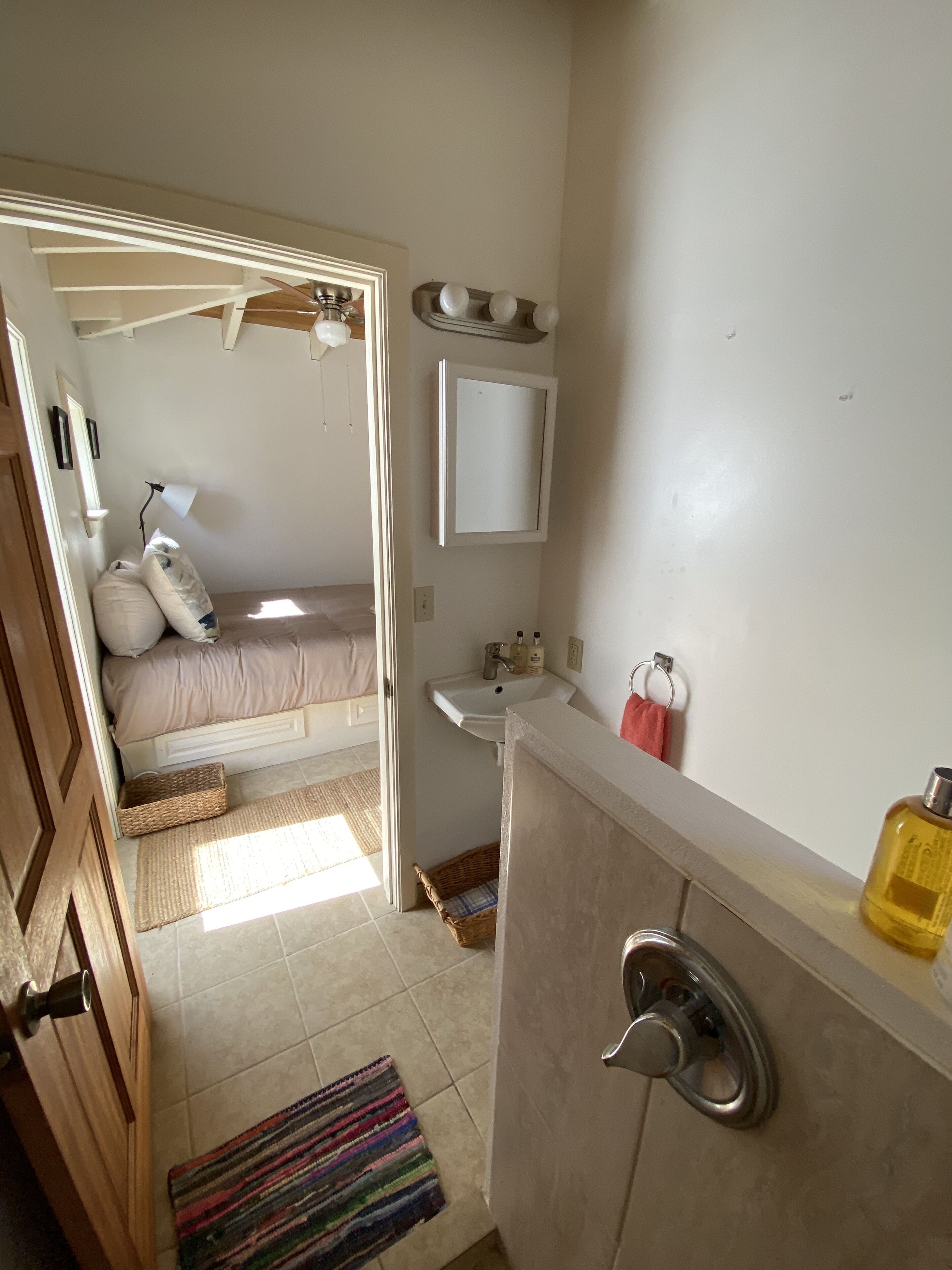 A bedroom with a bed, a bedside table, a nightstand, a window, and a door.