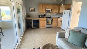 A modern kitchen with wooden cabinets, a microwave, a refrigerator, and a ceiling fan. - Water Island Cottage with a View  (St Thomas)