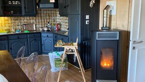 Ett modernt kök med mörka skåp, ett matbord i trä och en vedeldad kamin.