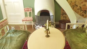 Una habitación acogedora con chimenea, una mesa redonda y dos sillones tapizados en verde.