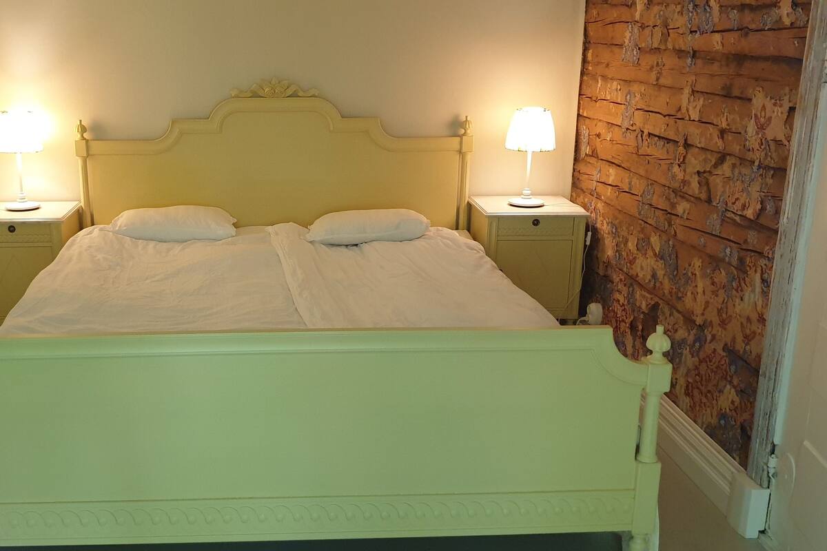 A bed with a headboard, two bedside tables, and two lamps.
