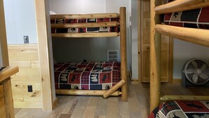 Ein Schlafraum mit Etagenbetten, Holzboden und einer gemusterten Decke.