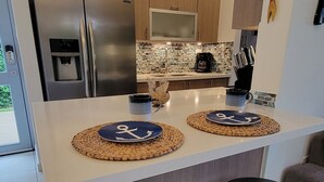 A modern kitchen with stainless steel appliances, a central island with stools, and decorative wall art. - ***CASA PALMA*** Tropical Caribbean Beach House (Rincon)