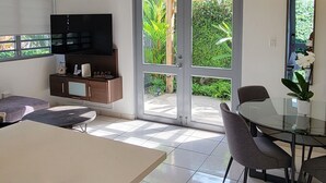 A modern kitchen with a dining area, a TV, and a view of greenery outside. - ***CASA PALMA*** Tropical Caribbean Beach House (Rincon)