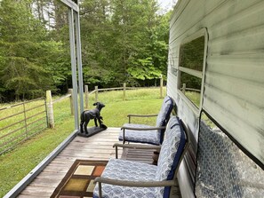 A covered porch with two patterned chairs and a metal sculpture of a dog. - LET'S GO CAMPING ~ CATTLE VIEW CAMPER (Ararat)