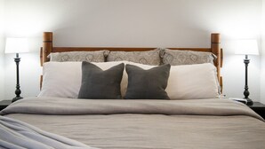 A neatly made bed with a grey blanket, two bedside lamps, and a wooden headboard.